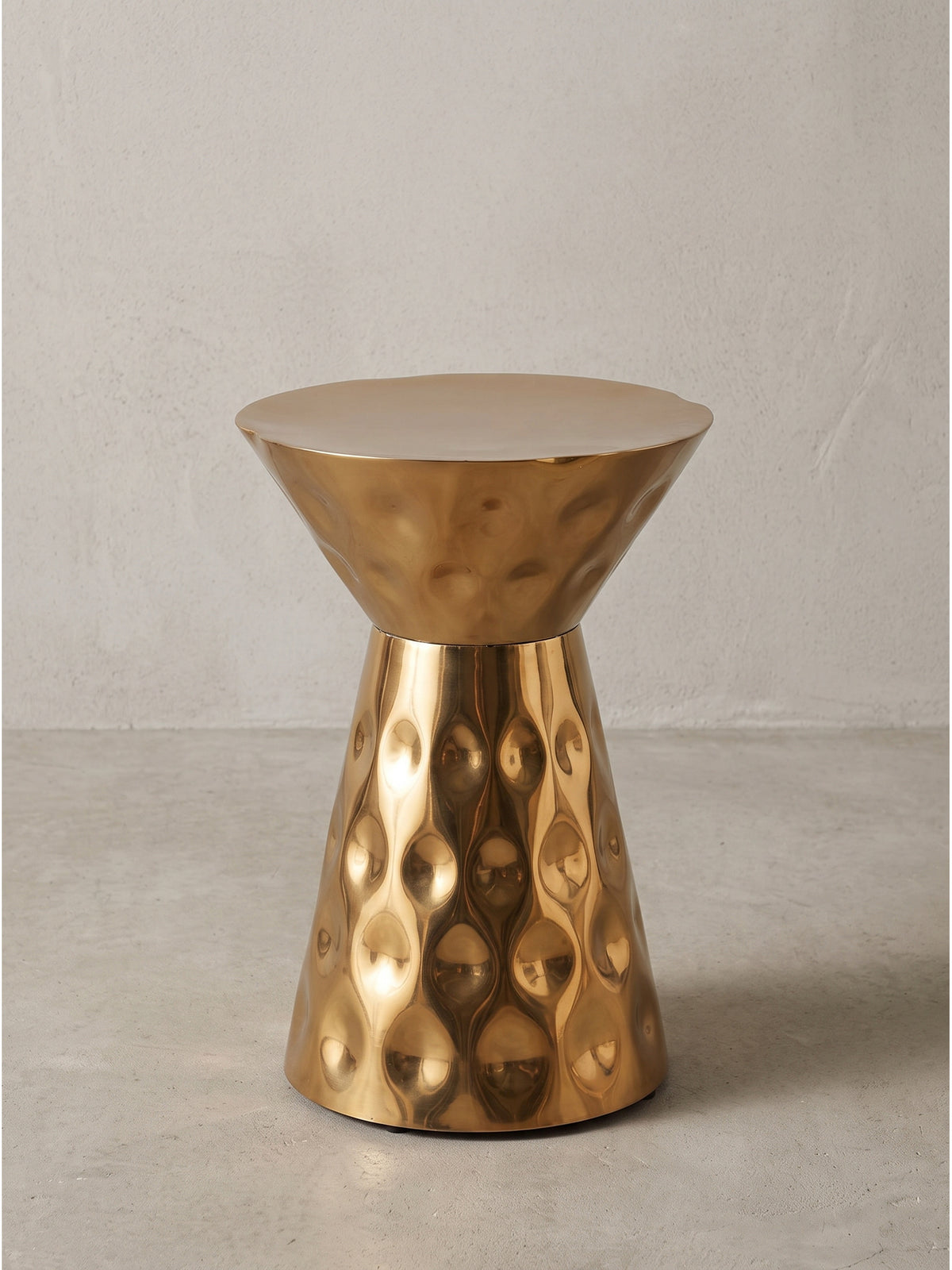 Detailansicht der gehämmerten Oberfläche des goldenen Beistelltischs aus Aluminium mit feinen Lichtreflexen_