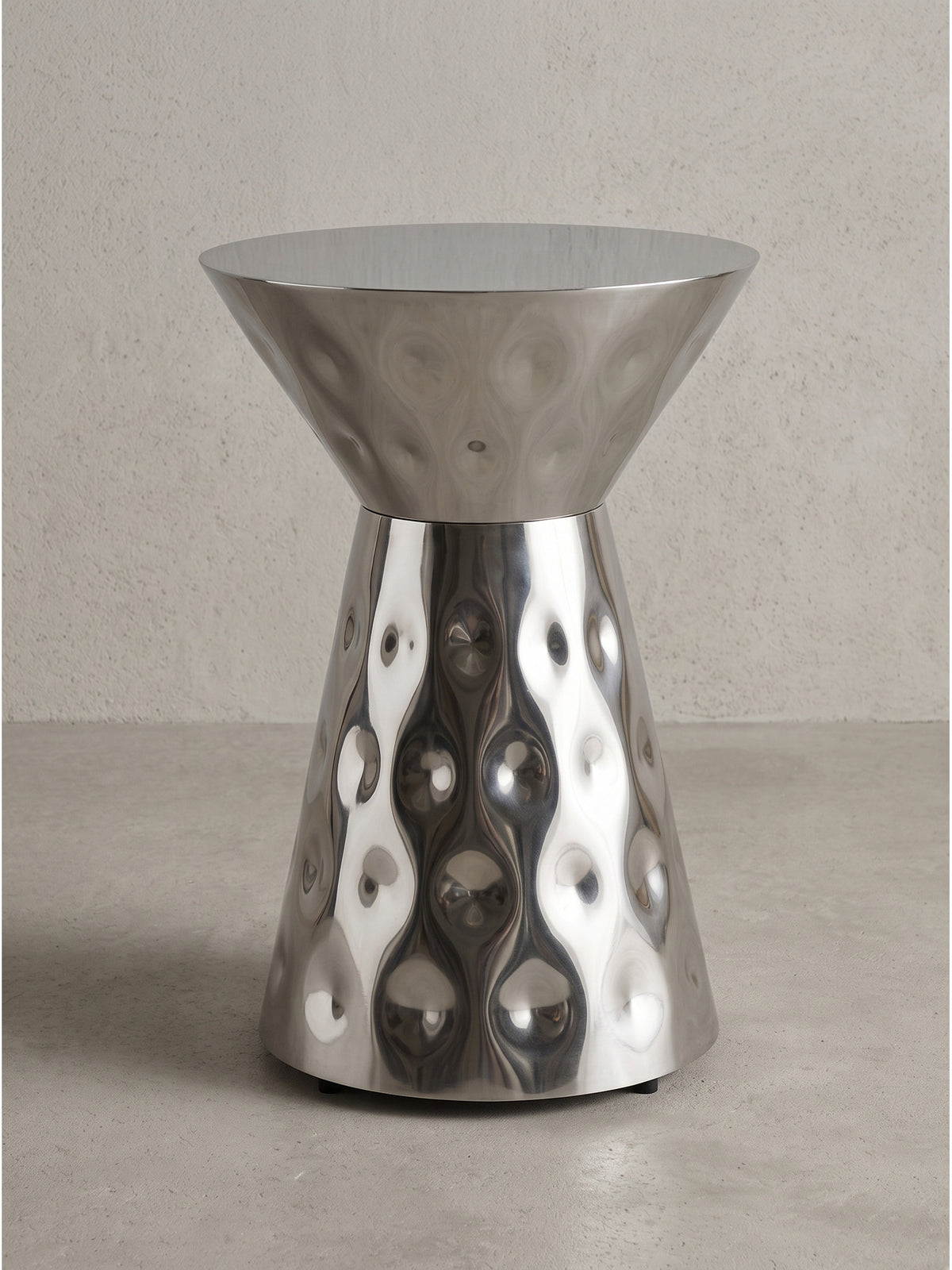 Handgefertigter Beistelltisch aus Aluminium 36x51 cm in Silber mit runder Platte und markant taillierter Form vor weißem Hintergrund._