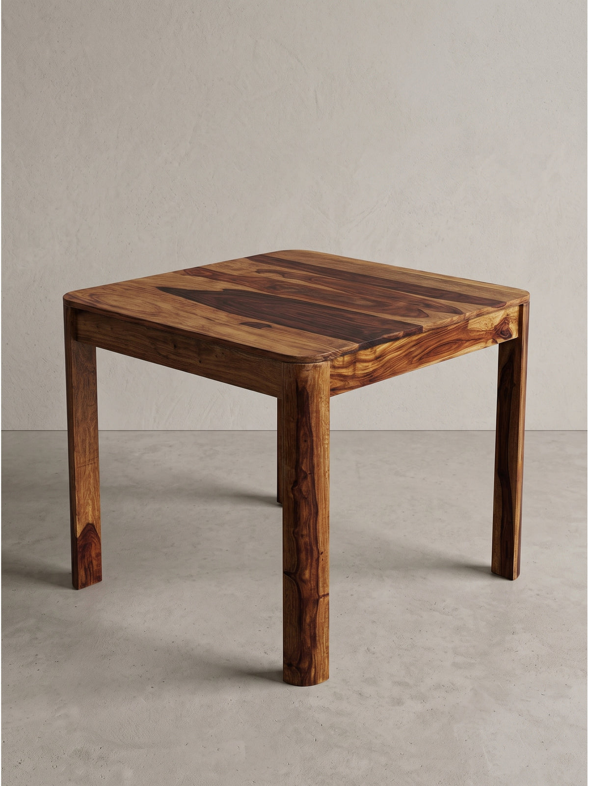Bistrotisch Sheesham 80x80 cm aus seitlicher Perspektive betont die leicht abgerundeten Kanten der massiven Tischplatte._
