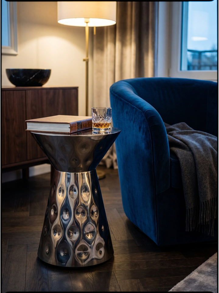 Moderner Loungetisch aus Aluminium mit einem schweren Kristallglas und einem Kunstband dekoriert in einer gemütlichen Leseecke._