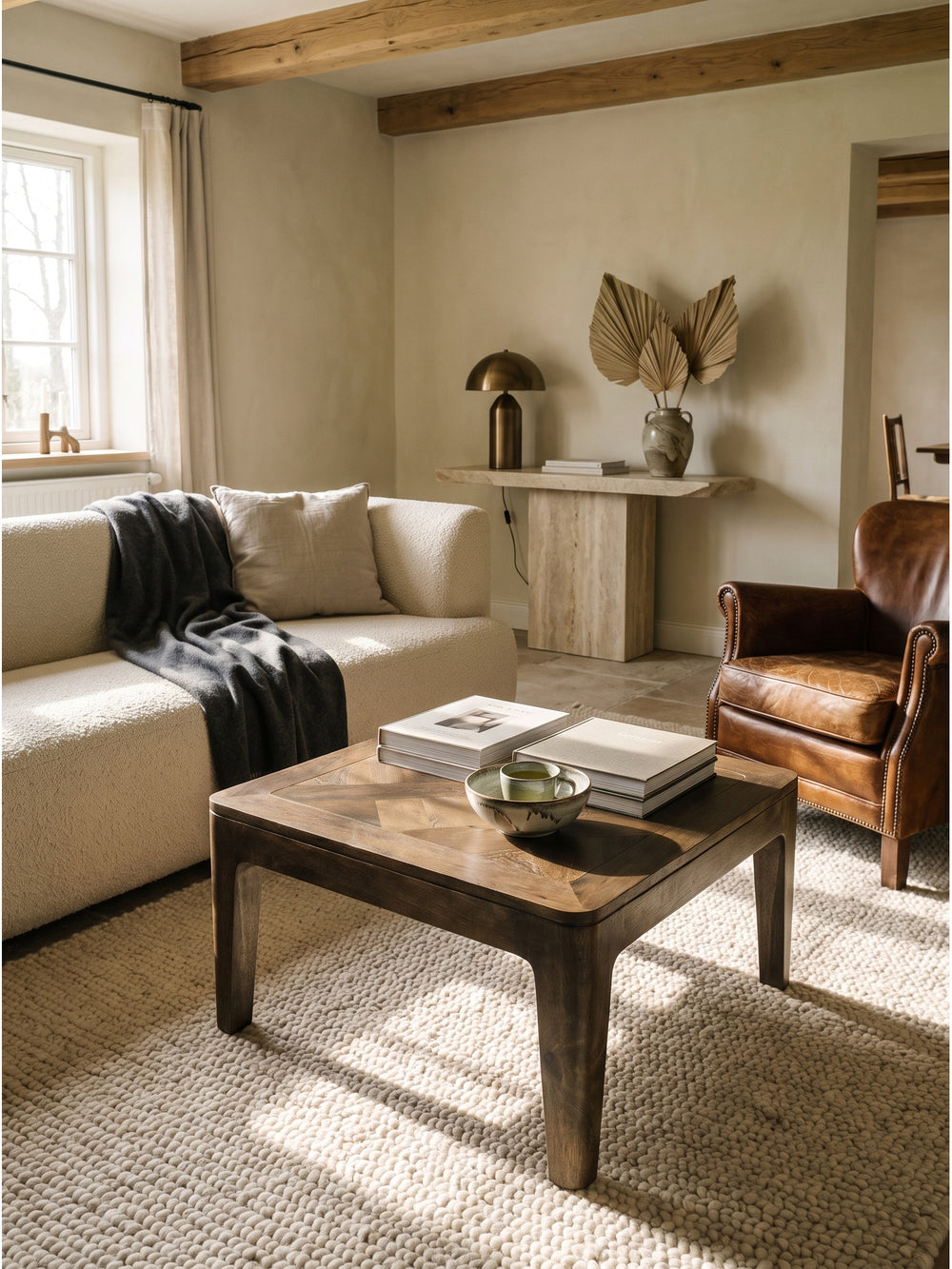 Flacher Sofatisch aus dunklem Mangoholz elegant kombiniert mit hellen Polstermöbeln und einer skulpturalen Travertin-Stehlampe._