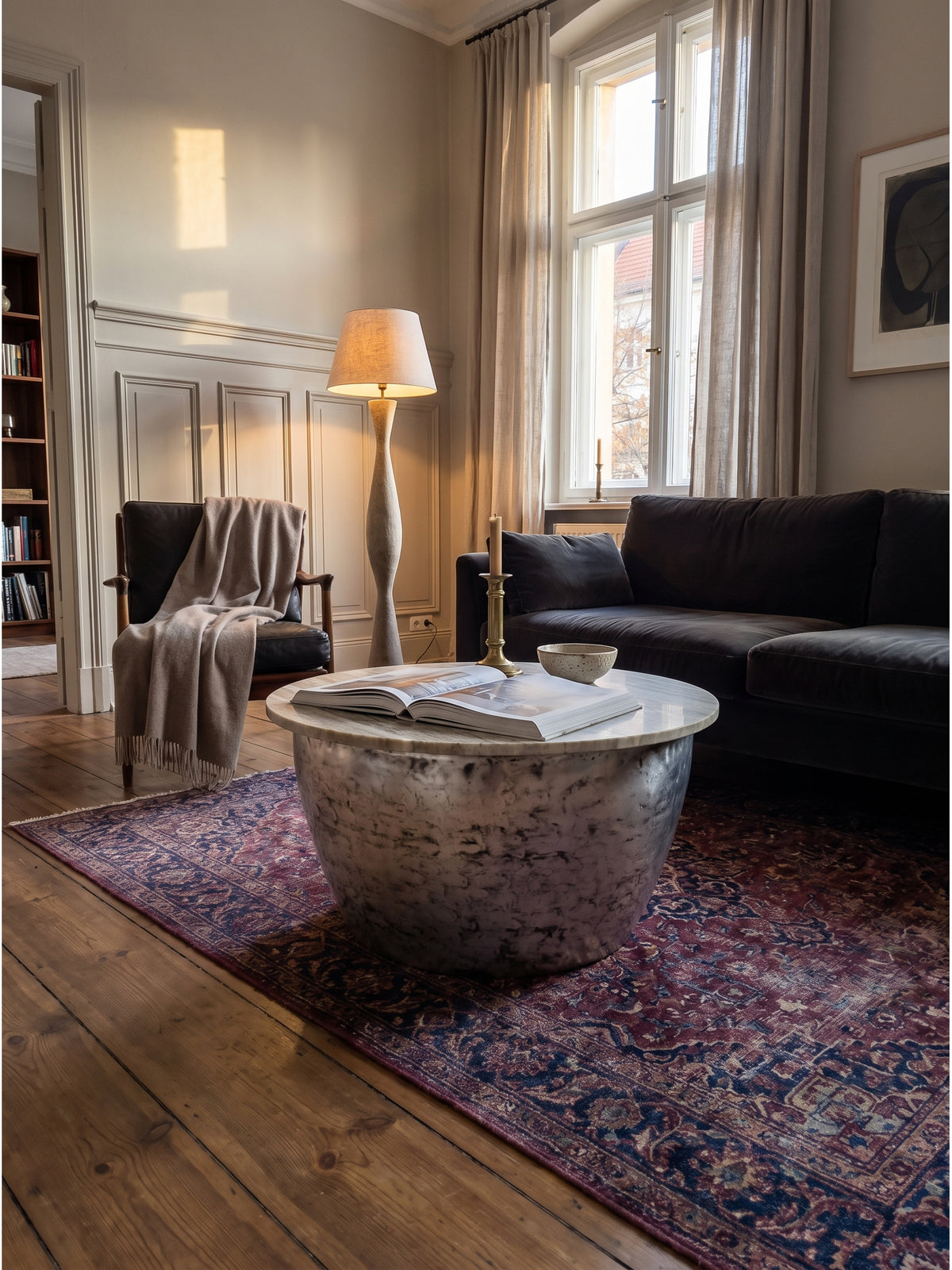 Kombination aus silbernem Metall Sofatisch mit Marmorplatte und einem dunklen Polstersofa in einem eleganten Wohnzimmer mit hohen Decken_
