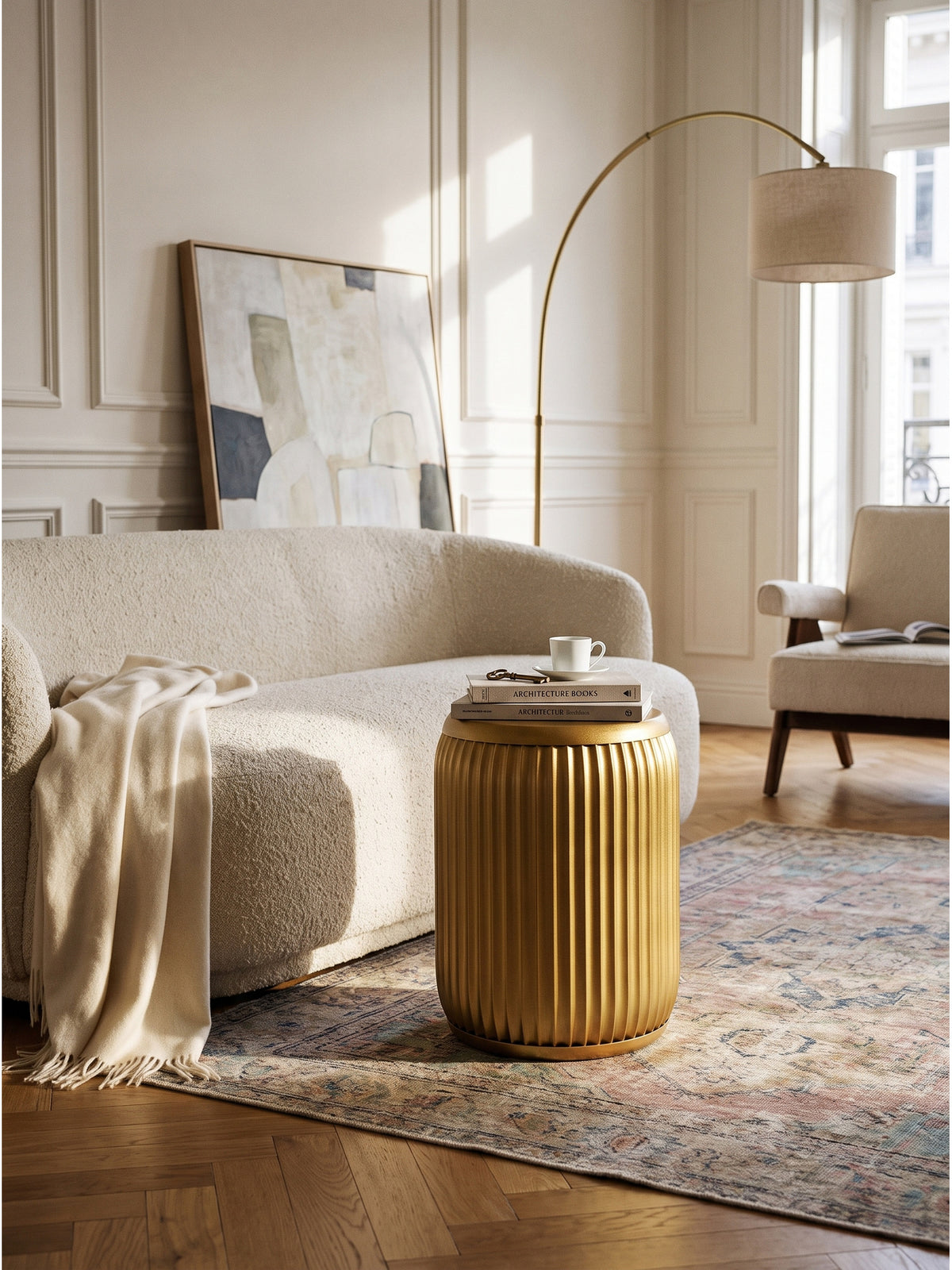 Goldener Sofatisch 35 cm Durchmesser im Wohnzimmer mit einer Keramikvase dekoriert neben einem beigefarbenen Bouclé-Sofa vor weißer Wandpaneele_