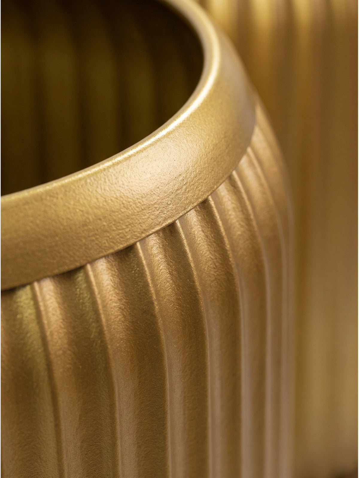 Nahaufnahme der vertikalen Rillenstruktur des goldenen Metalltisches zeigt das lackierte Finish und die präzise Verarbeitung des Zylinders_