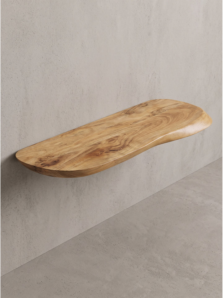 Schrägansicht des Massivholz Wandboards aus Akazie im Raum, das die schwebende Leichtigkeit an einer cremeweißen Wand demonstriert._