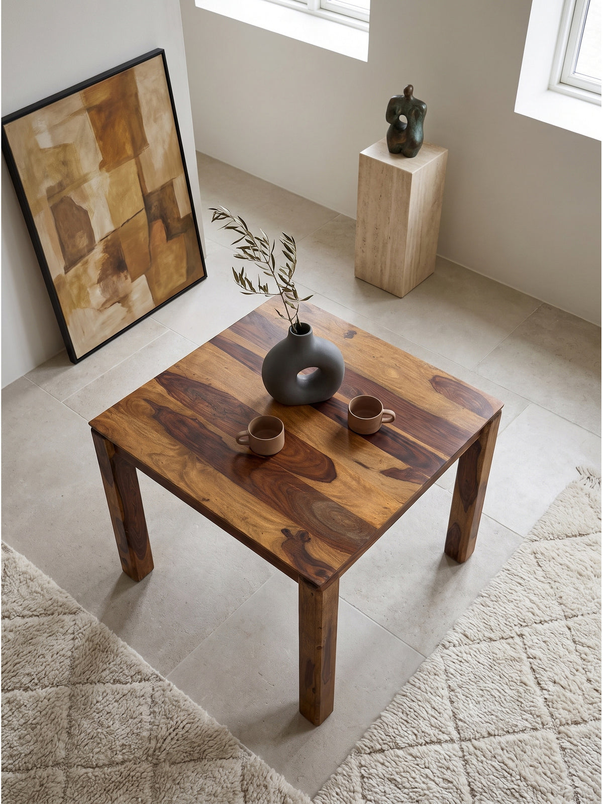 Aufsicht auf einen kompakten 80x80 cm Bistrotisch aus braunem Echtholz auf einem hellen handgeknüpften Wollteppich