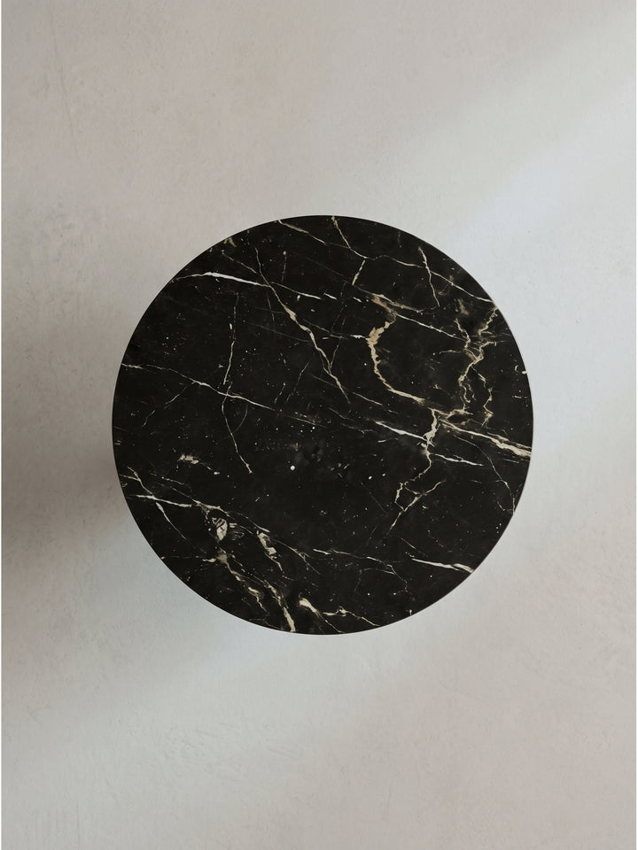 Der schwarze Marmor-Couchtisch mit goldenem Fuß im Art-Déco Design freigestellt vor weißem Hintergrund mit Fokus auf die glatte Natursteinfläche._