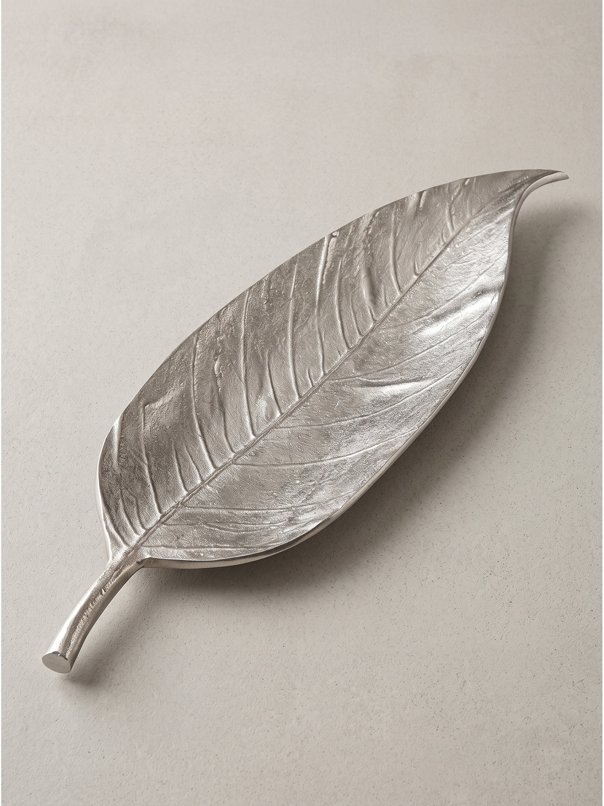Silberne Metallschale im Blatt-Design schräg von der linken Seite betrachtet mit glänzender Oberfläche_