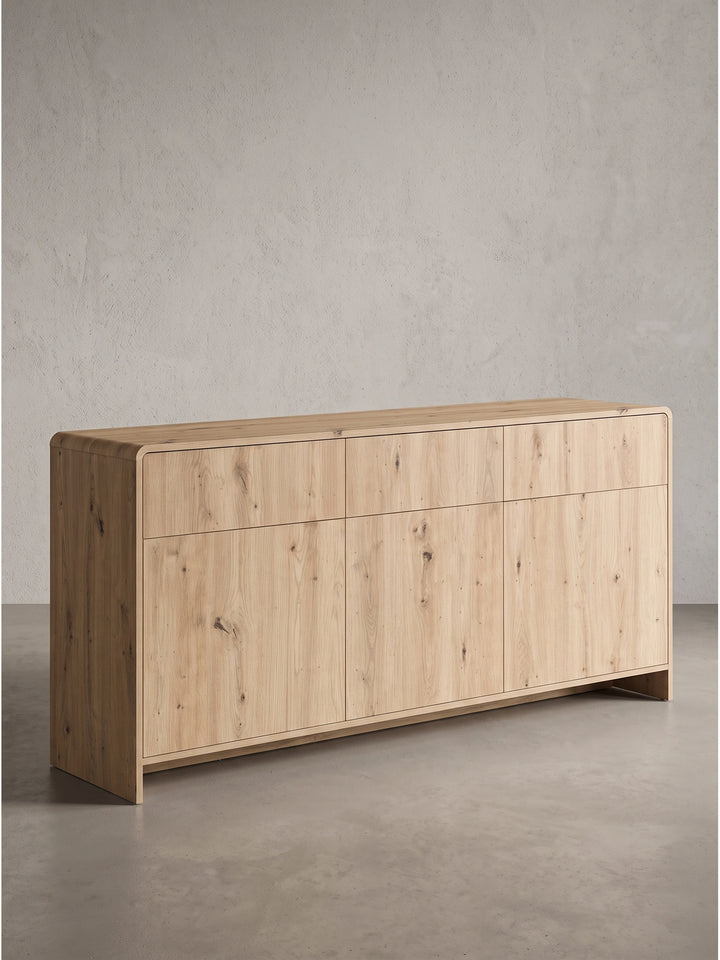 Seitenprofil des grifflosen Sideboards in Eiche Dekor, das die flächenbündigen Fronten und das durchgehende Sockeldesign zeigt._