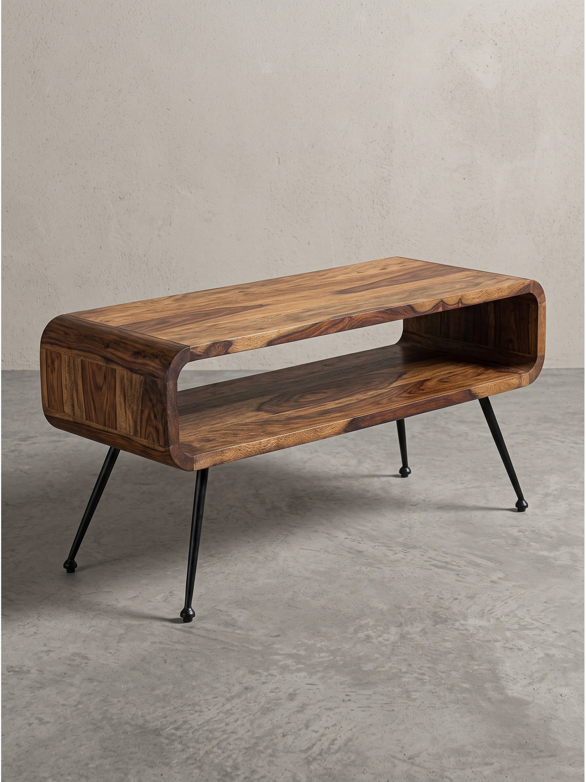 Frontansicht des 100x40 cm großen Couchtischs aus Sheeshamholz mit markant abgerundeten Ecken und schwarzen Metallbeinen freigestellt vor weißem Hintergrund._