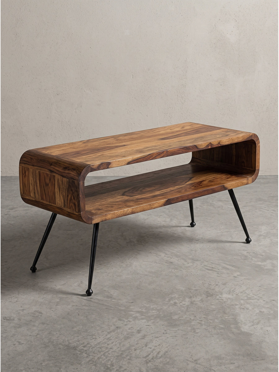 Frontansicht des 100x40 cm großen Couchtischs aus Sheeshamholz mit markant abgerundeten Ecken und schwarzen Metallbeinen freigestellt vor weißem Hintergrund._