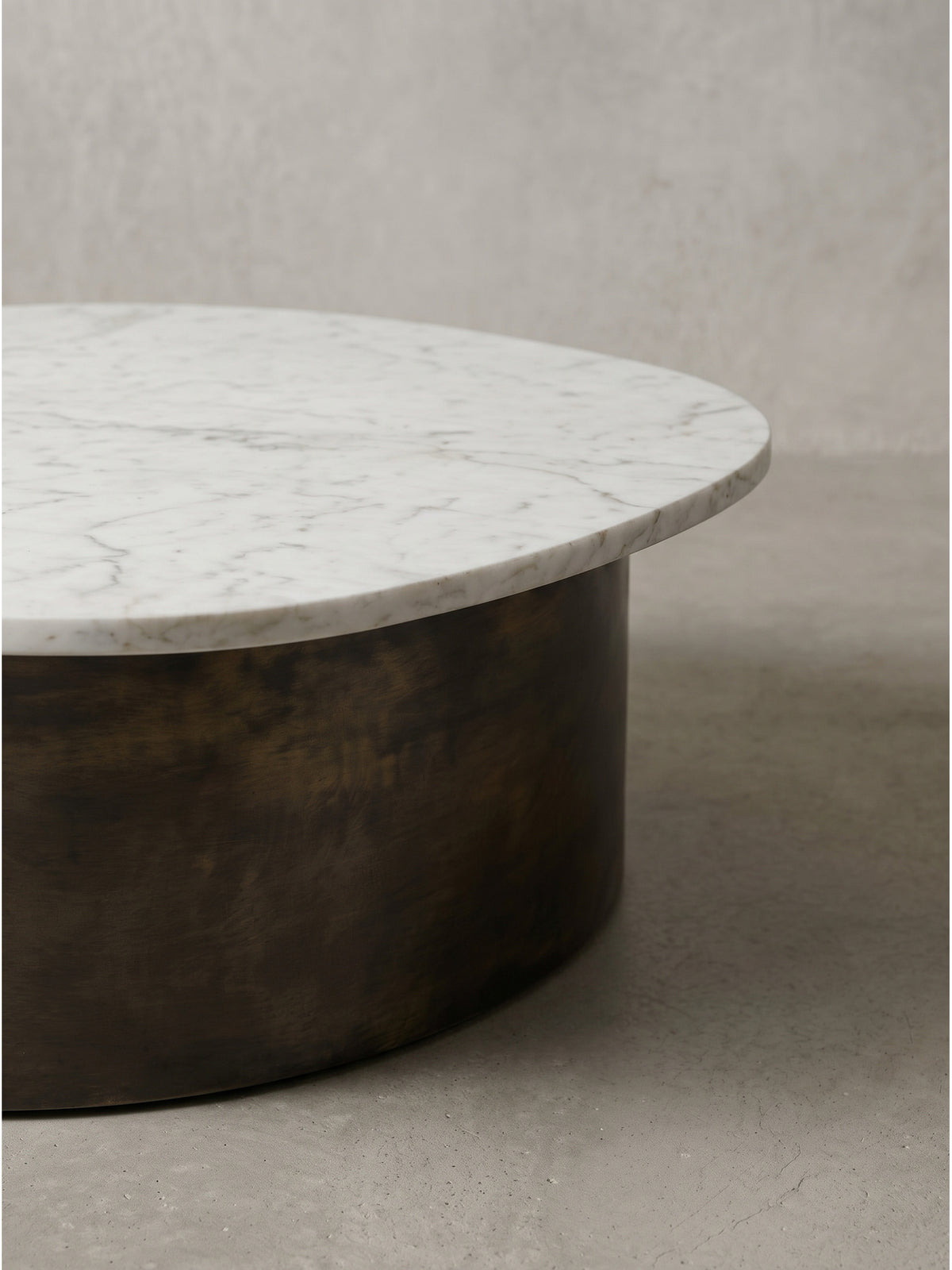 Perspektivische Ansicht des Design-Beistelltisches 63cm offenbart den Kontrast zwischen kühlem weißen Stein und warmem dunklen Metall_