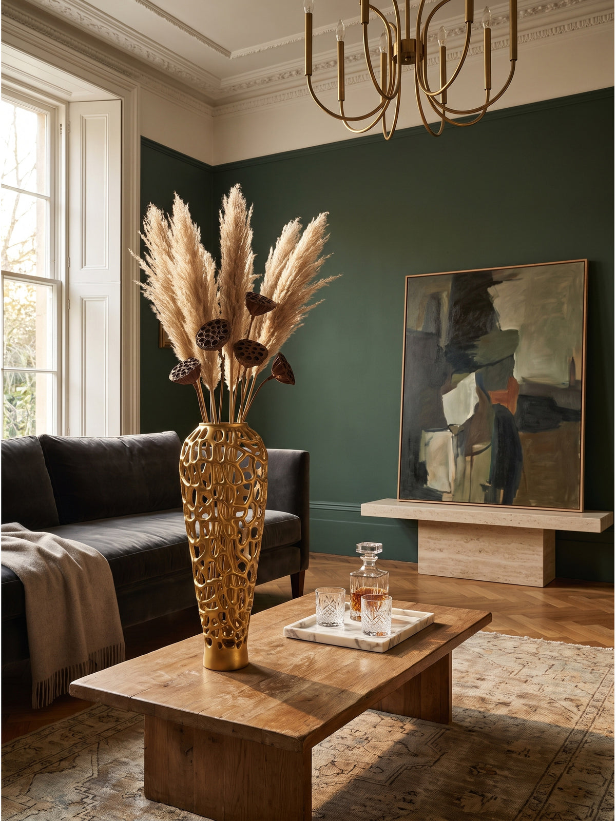 Große Bodenvase aus Aluminium in Gold 60 cm hoch mit organischem Lochmuster im luxuriösen Wohnzimmer neben dunkelgrauem Sofa auf Eichenparkett_