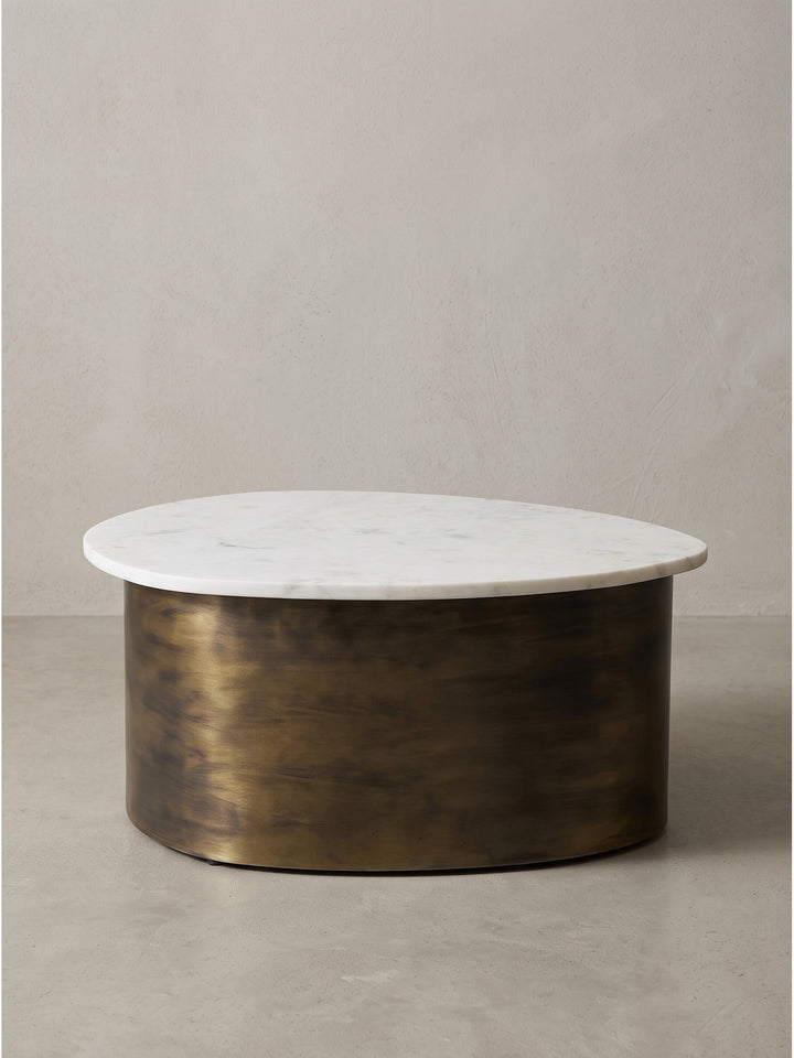 Seitenansicht des minimalistischen Wohnzimmertisches mit geschlossenem zylindrischen Metallgestell und überstehender Marmorplatte_