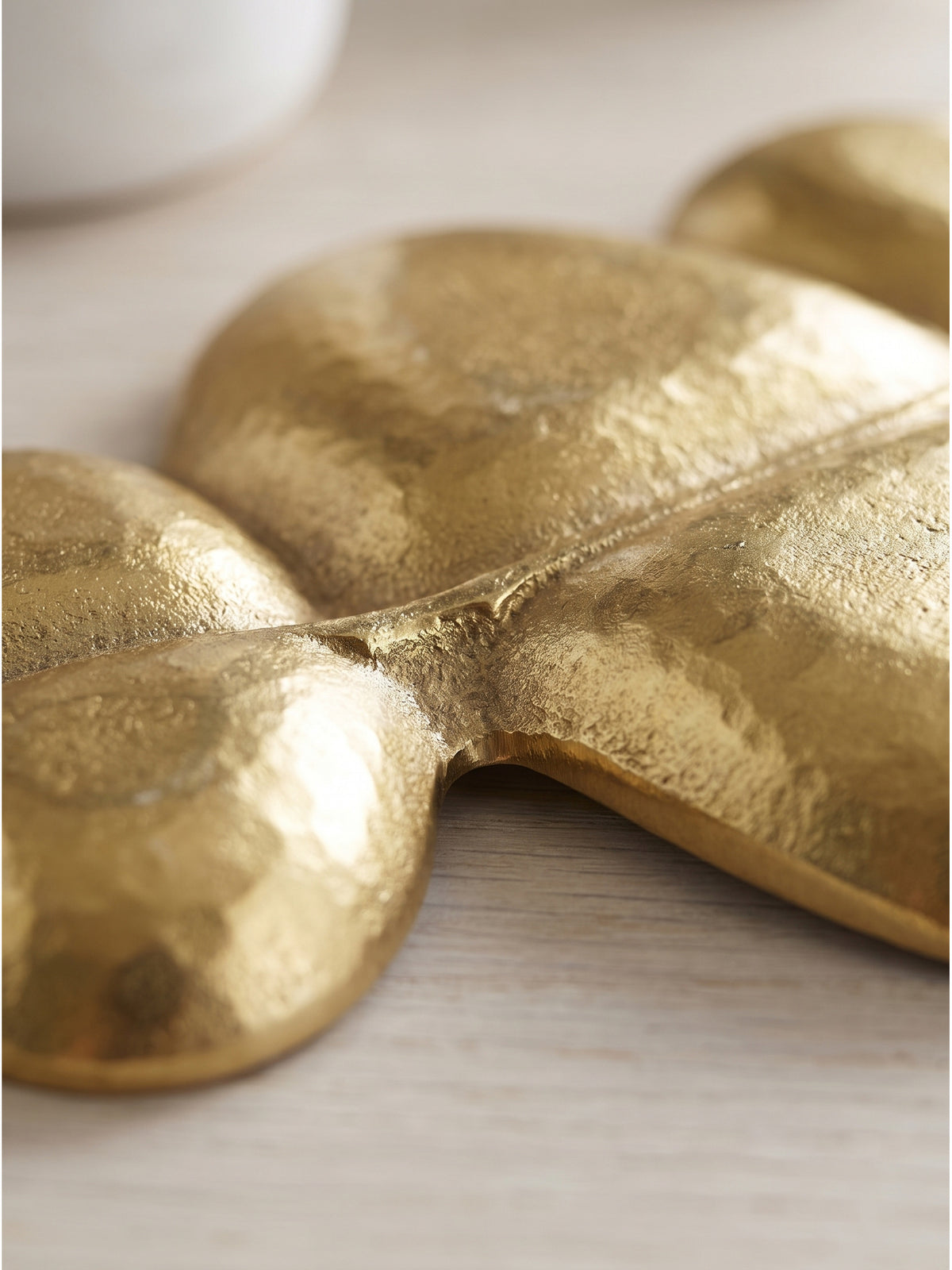 Nahaufnahme der gehämmerten goldenen Oberfläche der dekorativen Metallschale in Blattform_