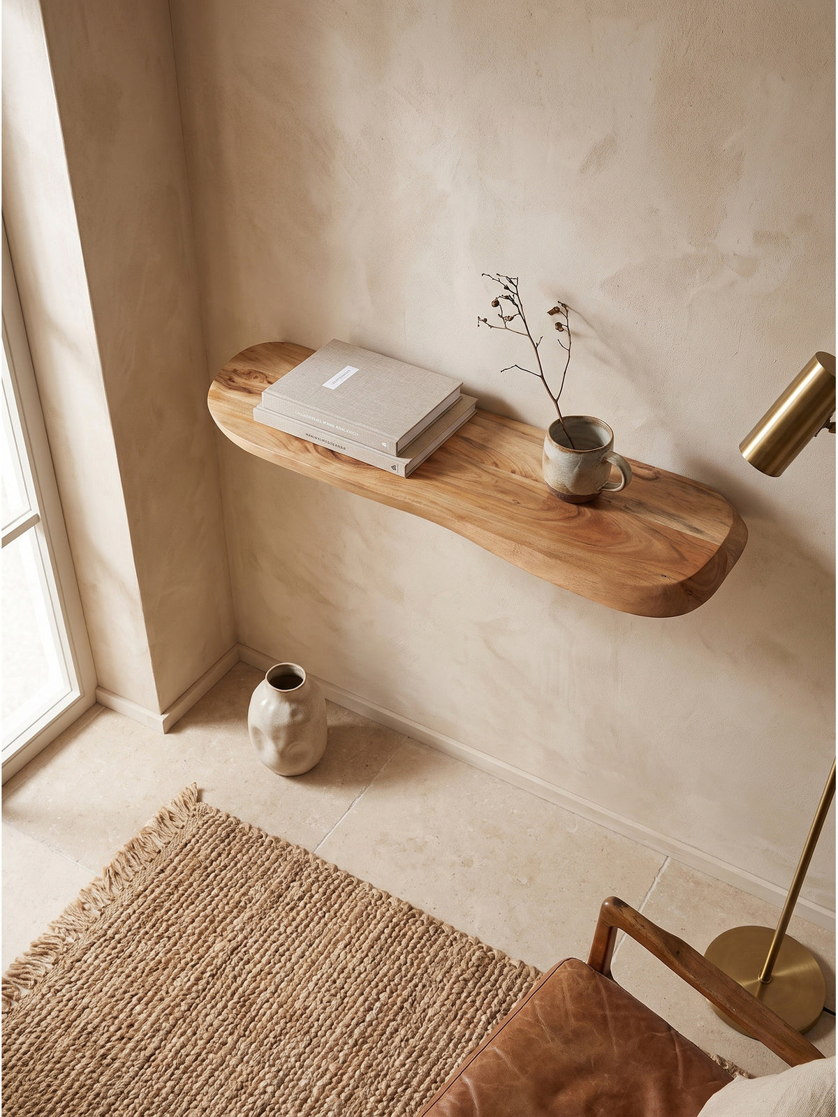 Draufsicht auf das Akazienholz Regal mit organischer Form im minimalistischen Raum über einem Rattansessel_