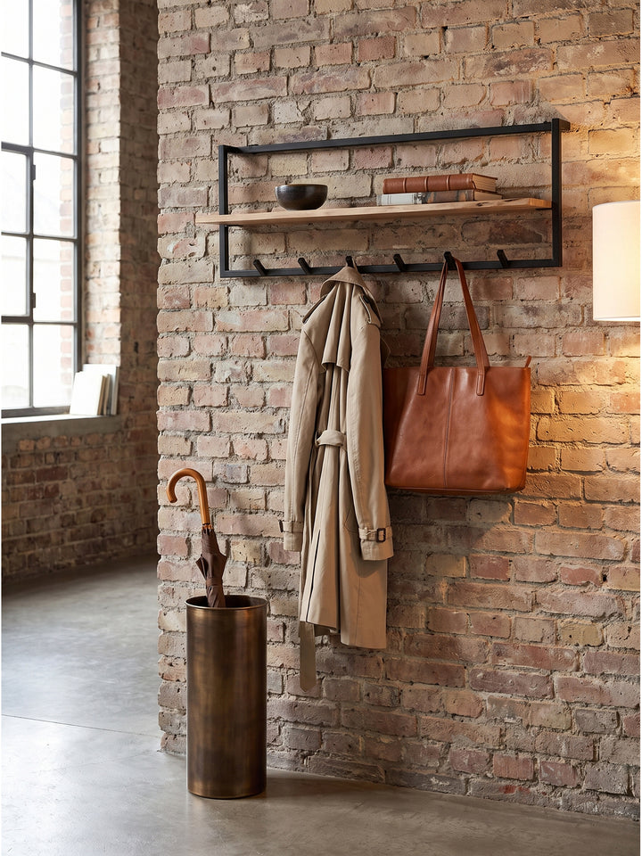 Eingangsbereich mit einer Garderobe im Industrial-Stil, einem beigen Trenchcoat an den Haken und Keramik auf der Ablage._