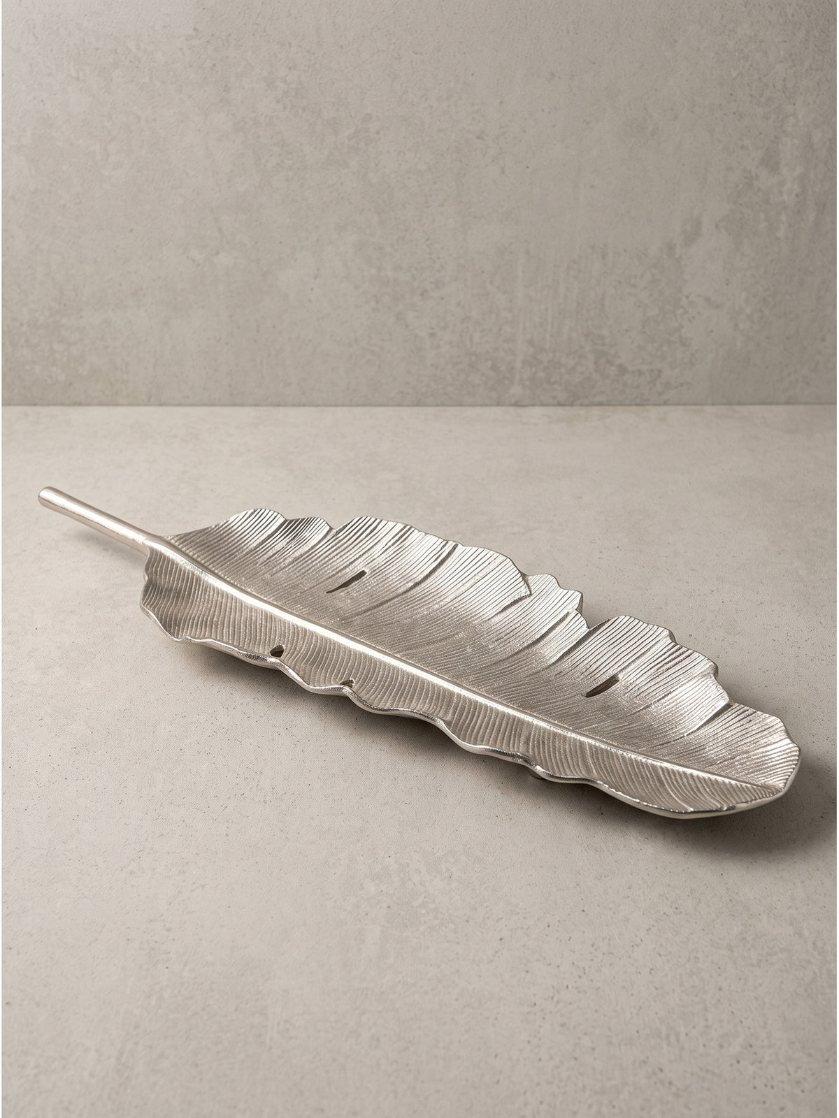 Vollansicht der 80 cm langen, geschwungenen Dekoschale aus silbernem Aluminium mit markantem Blattstiel auf weißem Hintergrund.