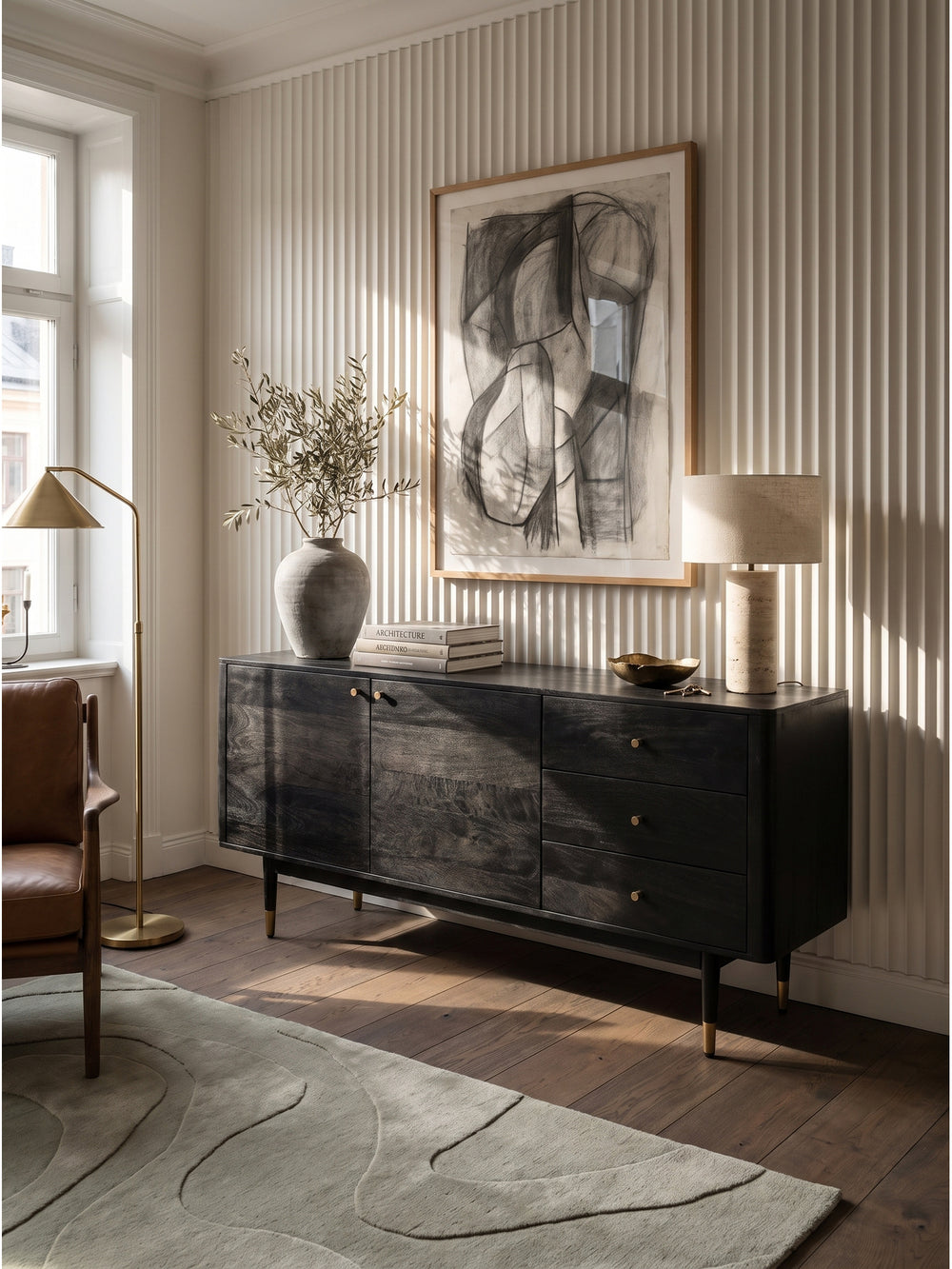 Elegantes Sideboard aus schwarzem Akazienholz mit feinen Messing-Griffen im modernen Wohnzimmer vor einer warmweißen, gerippten Wand._
