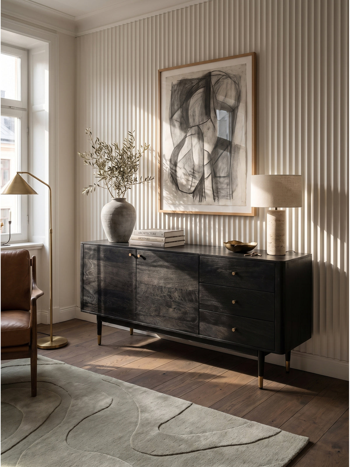 Elegantes Sideboard aus schwarzem Akazienholz mit feinen Messing-Griffen im modernen Wohnzimmer vor einer warmweißen, gerippten Wand._