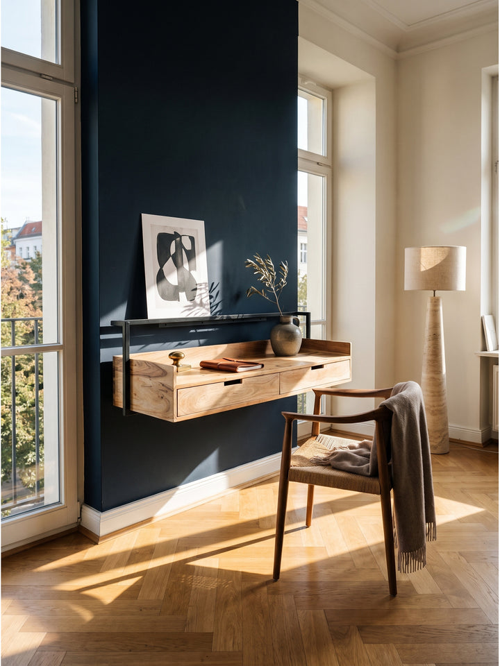 Schwebender Wandschreibtisch aus massivem Akazienholz an einer nachtblauen Wand im eleganten Home Office mit klassischem Eichenparkett._