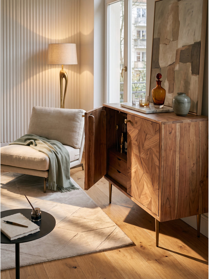 Handgefertigte Weinkommode in Naturholz kombiniert mit weichem Vintage-Teppich und skulpturaler Keramiklampe im Wohnbereich_