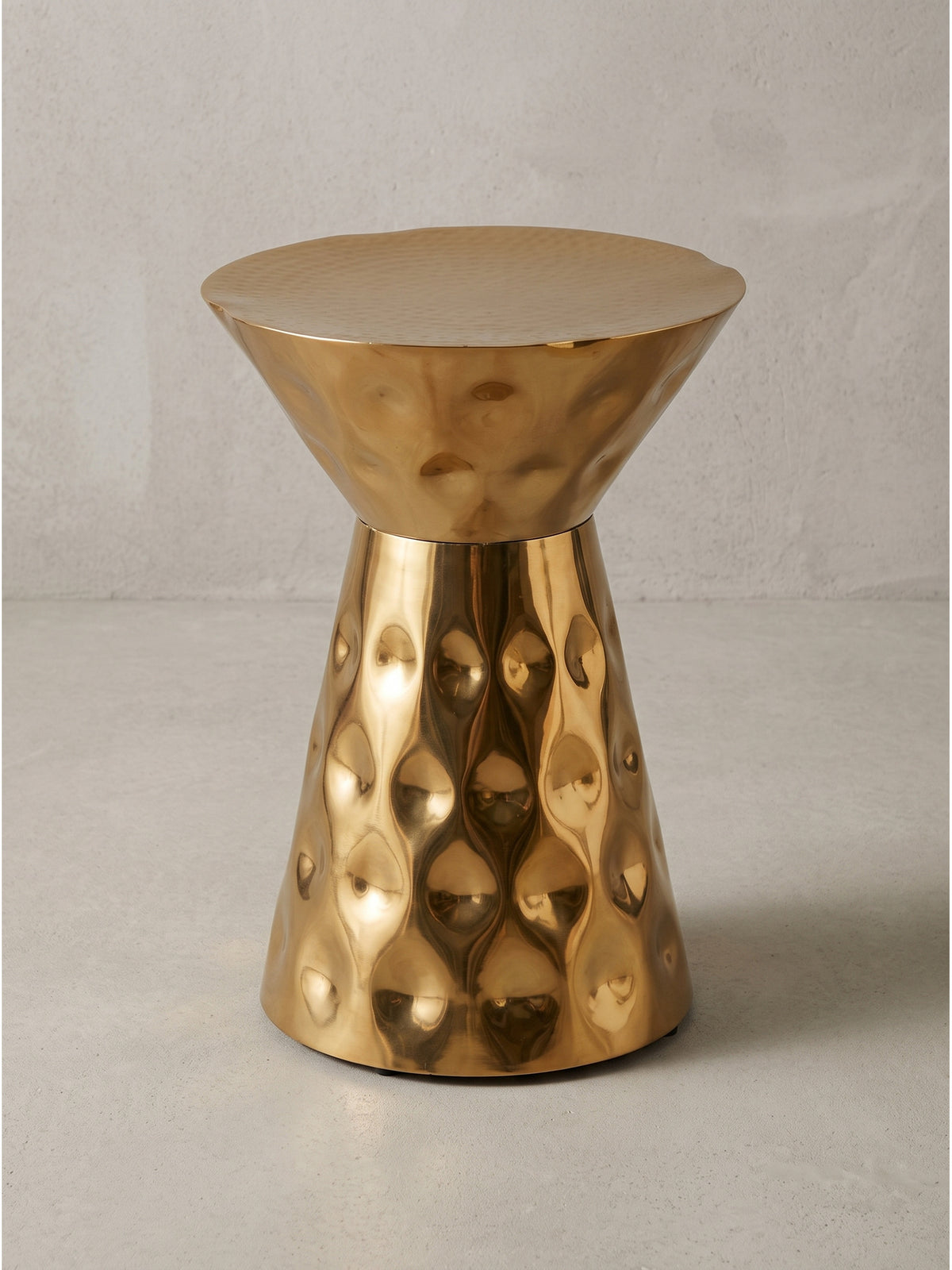Runder Beistelltisch aus Aluminium in Gold 36x51 cm in Sanduhrform vor weißem Hintergrund mit strukturierter Oberfläche_