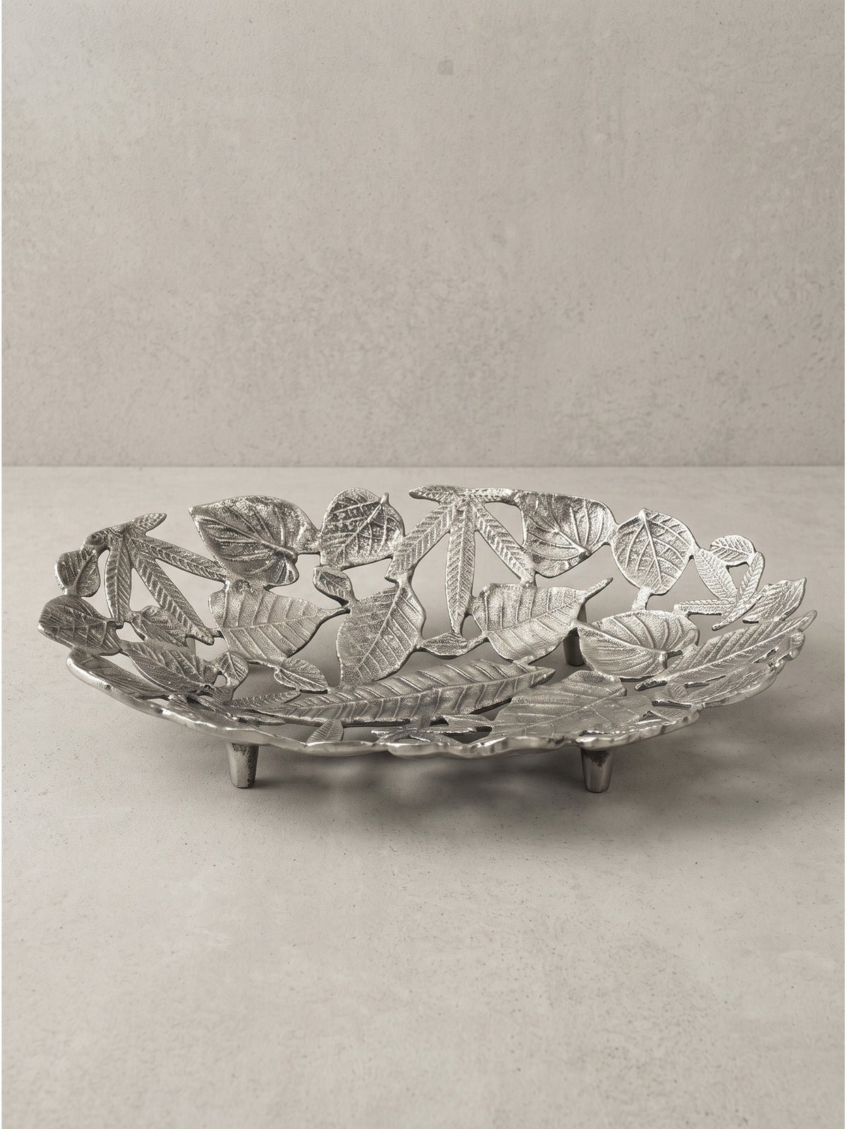 Ovale Metallschale aus leichtem Aluminium in Silber mit Blättermotiv und kleinen Standfüßen freigestellt_
