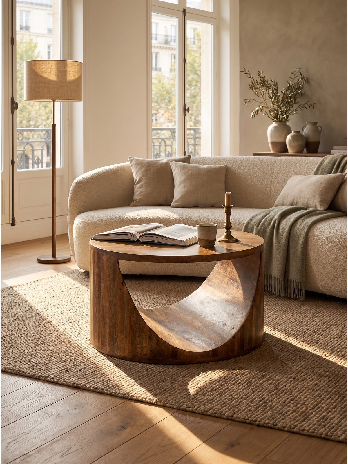 Naturholz Wohnzimmertisch mit geschwungener Ablagefläche arrangiert mit Kunstbüchern und Keramikvase im sonnendurchfluteten Raum