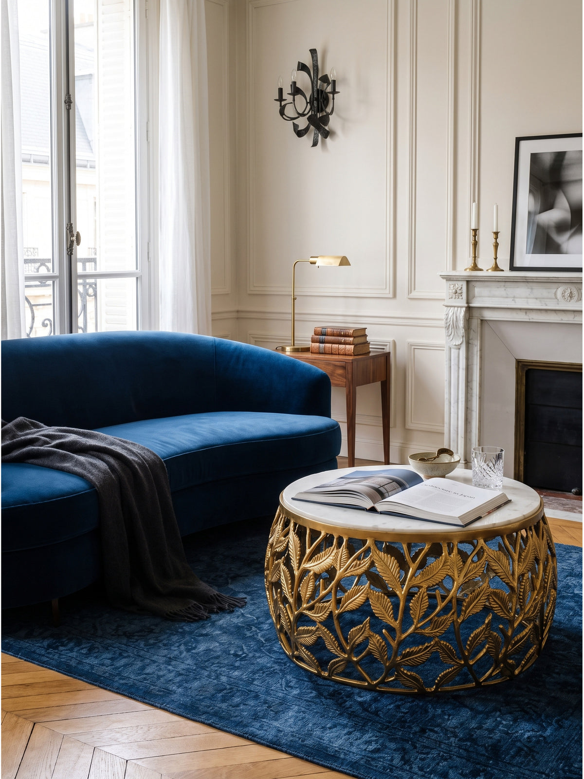 Runder Design-Couchtisch aus Gold und Marmor stilvoll kombiniert mit klassischen Polstermöbeln vor einer eleganten weißen Boiserie-Wand_
