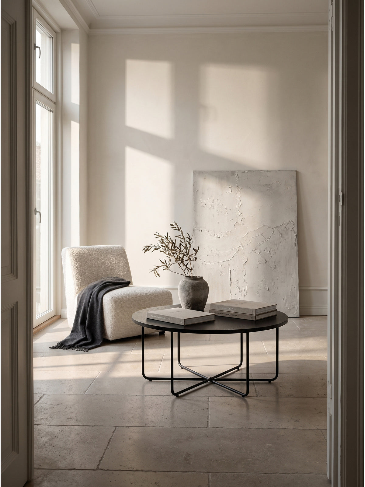 Minimalistischer runder Couchtisch aus schwarzer Eichenoptik und Stahlrohr als skulpturales Zentrum auf einem cremefarbenen Leinen-Teppich._