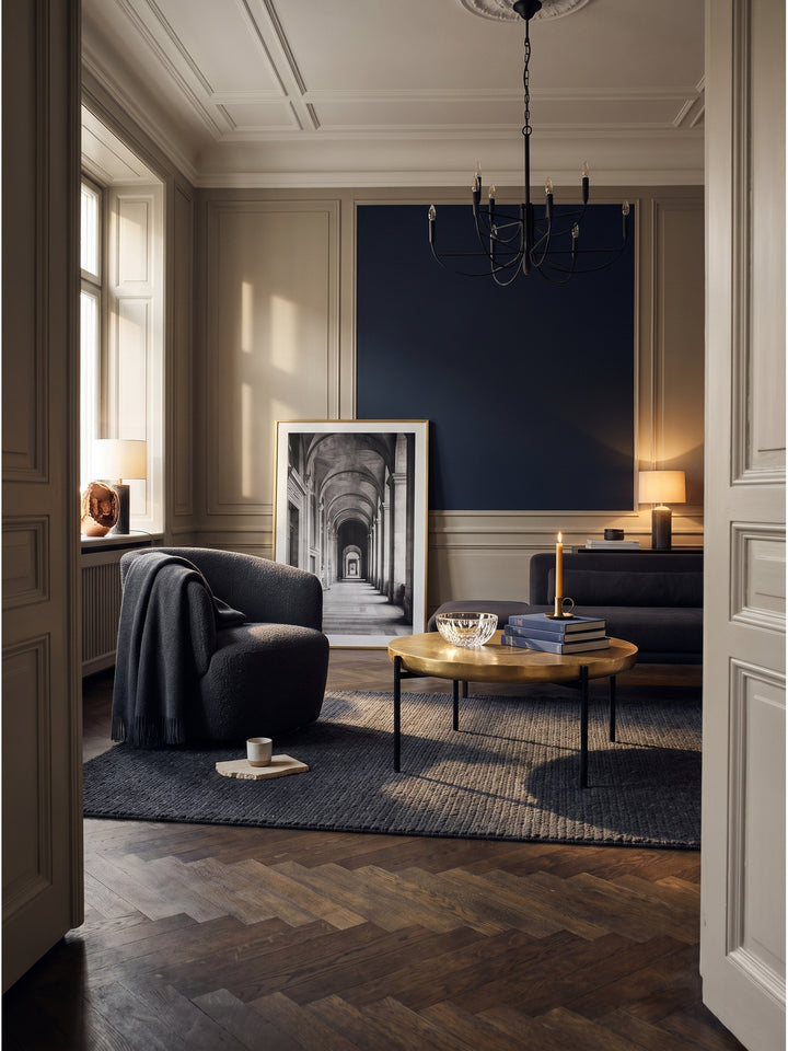 Runder Couchtisch aus Aluminium in glänzendem Gold 63x41 cm im eleganten Wohnzimmer vor einem samtenen Sofa auf dunklem Fischgrätparkett_