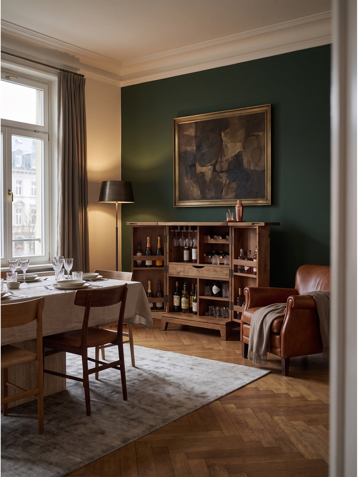 Handgefertigter Barschrank aus massivem Sheeshamholz mit brauner Maserung im eleganten Wohnzimmer vor einer tiefgrünen Akzentwand und neben einem Ledersessel._
