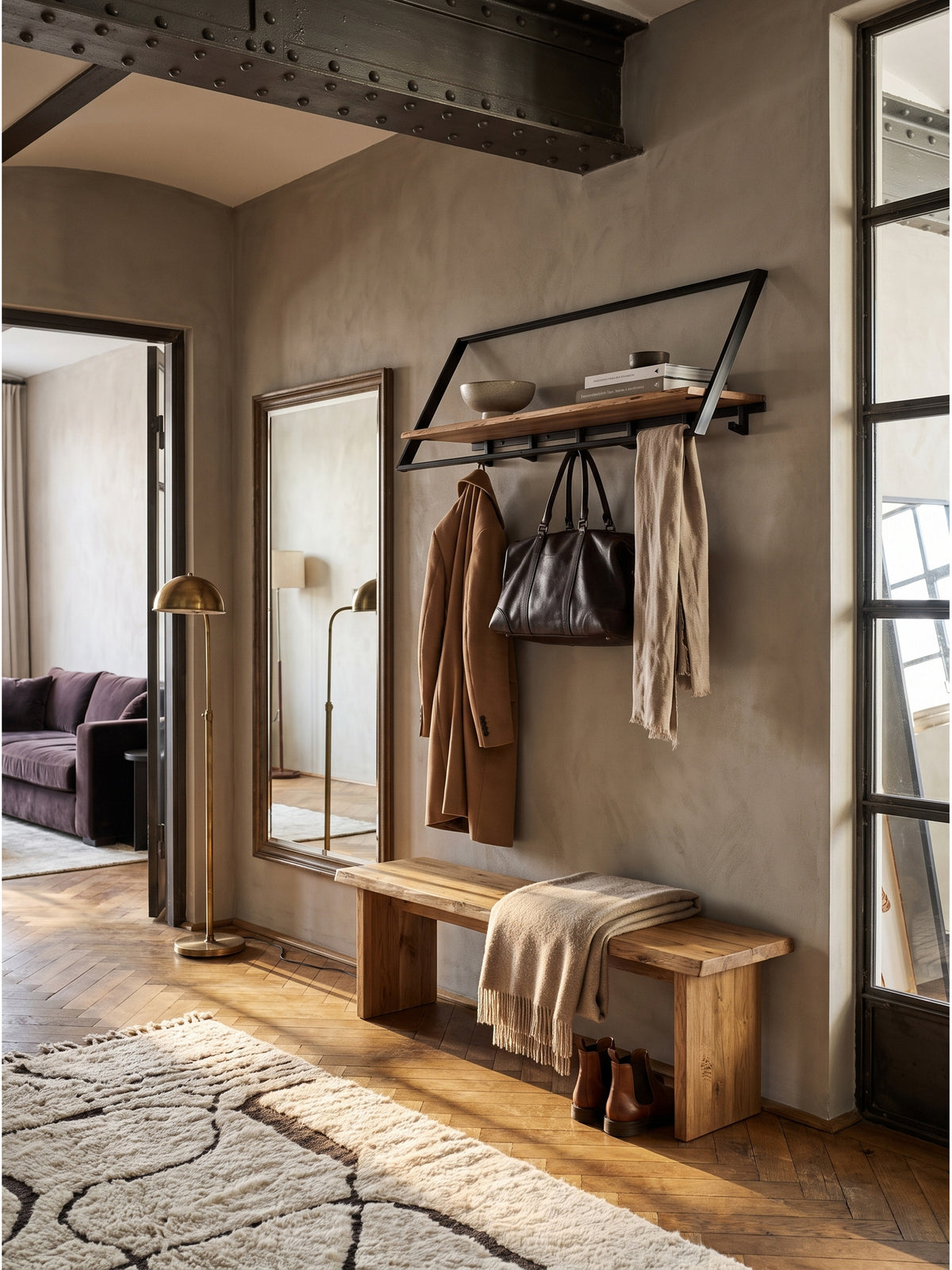 Die schwarze Metallgarderobe harmoniert perfekt mit einer Vintage-Holzbank und einem verblassten Oushak-Teppich im luxuriösen Entrée.