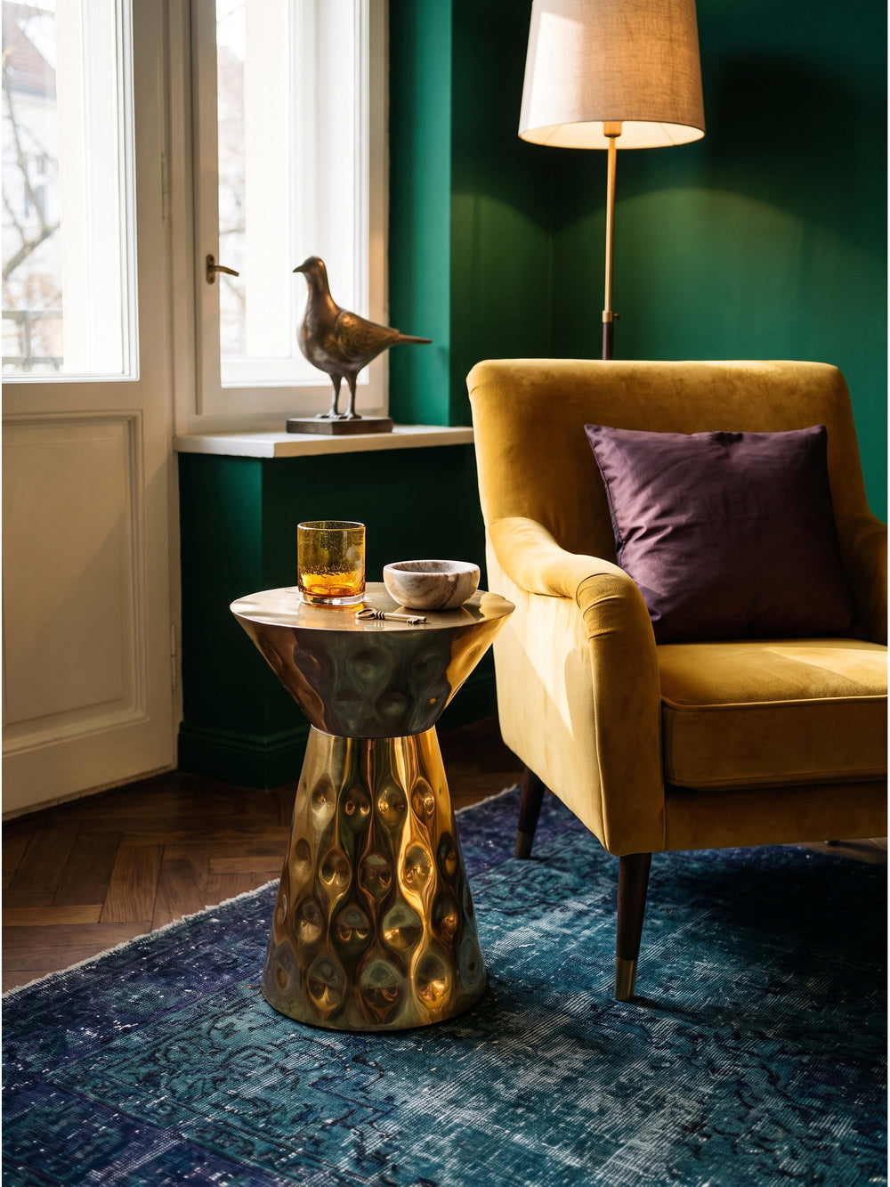 Moderner Metalltisch als Beistelltisch in Gold kombiniert mit einem Vintage-Teppich und einem schweren Samtsessel im Wohnzimmer_