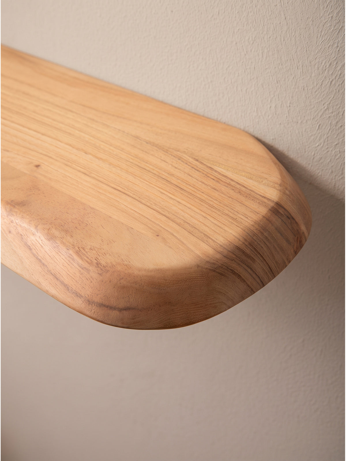 Schrägansicht des Hängeregals aus Naturholz mit abgerundeten Ecken, das schlichte Design fügt sich harmonisch in organisch inspirierte Raumkonzepte ein_