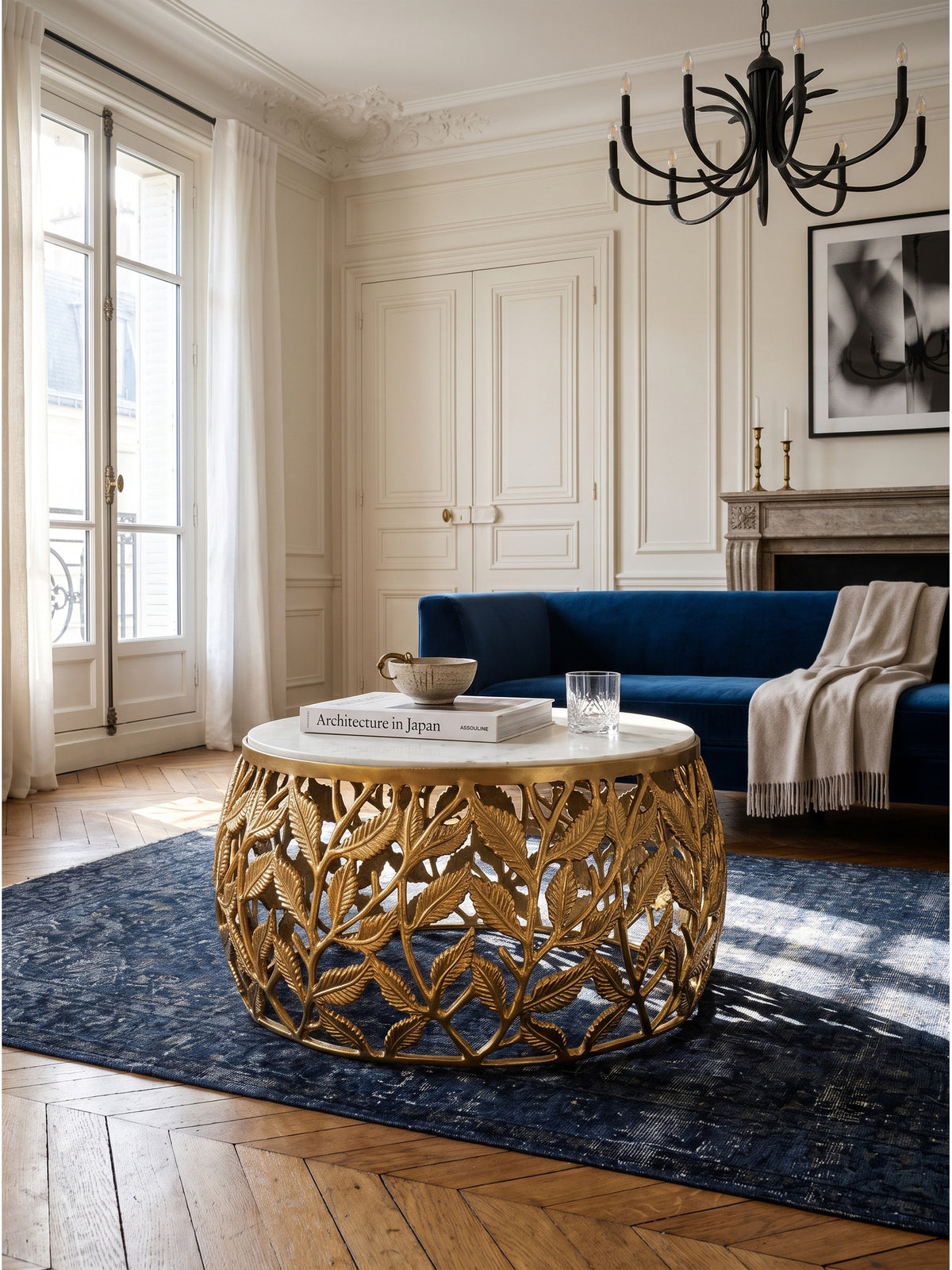 Eleganter runder Couchtisch mit goldfarbenem Blättergestell und massiver Marmorplatte in einem Pariser Wohnzimmer mit dunklem Eichenparkett_