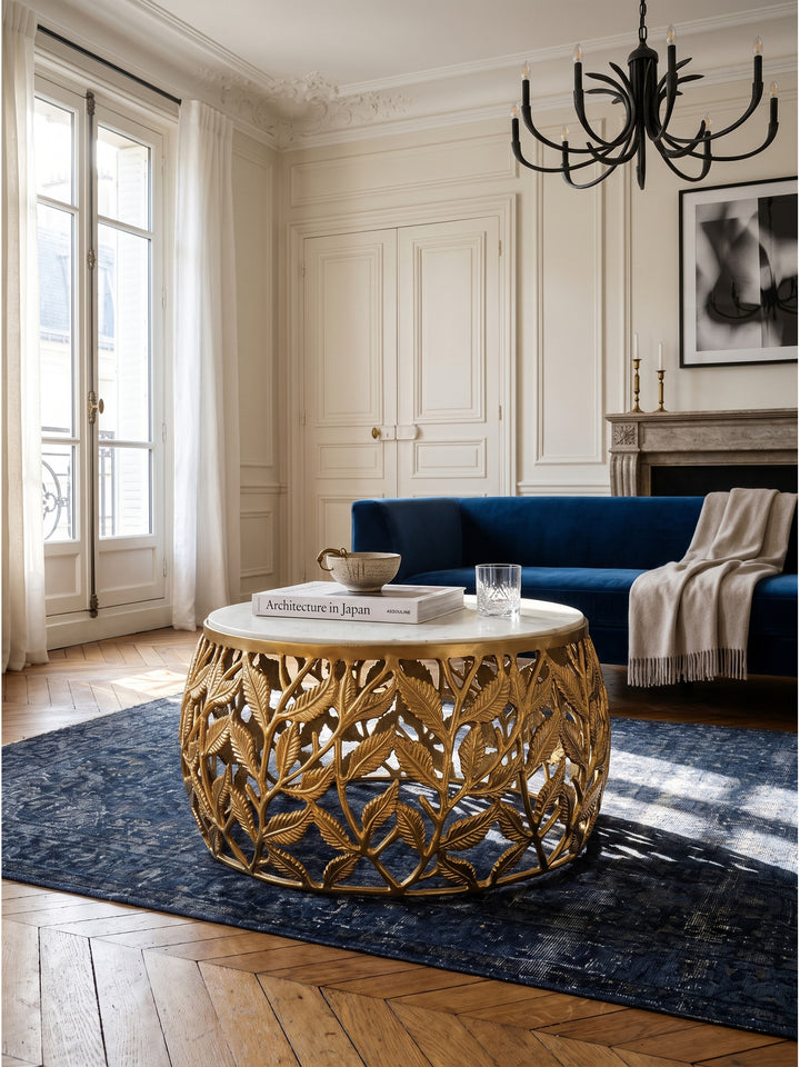 Eleganter runder Couchtisch mit goldfarbenem Blättergestell und massiver Marmorplatte in einem Pariser Wohnzimmer mit dunklem Eichenparkett_