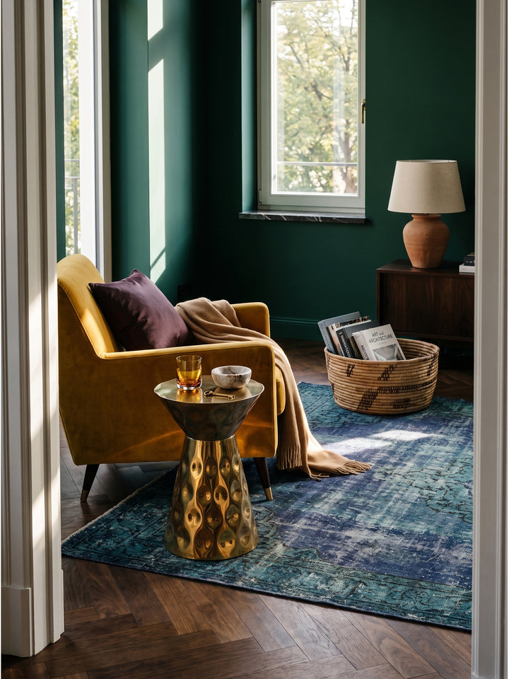 Gehämmerter Beistelltisch aus Aluminium in Gold 36x51 cm im Boho-Luxe Wohnzimmer vor smaragdgrüner Wand neben einem Senfgelben Sessel_