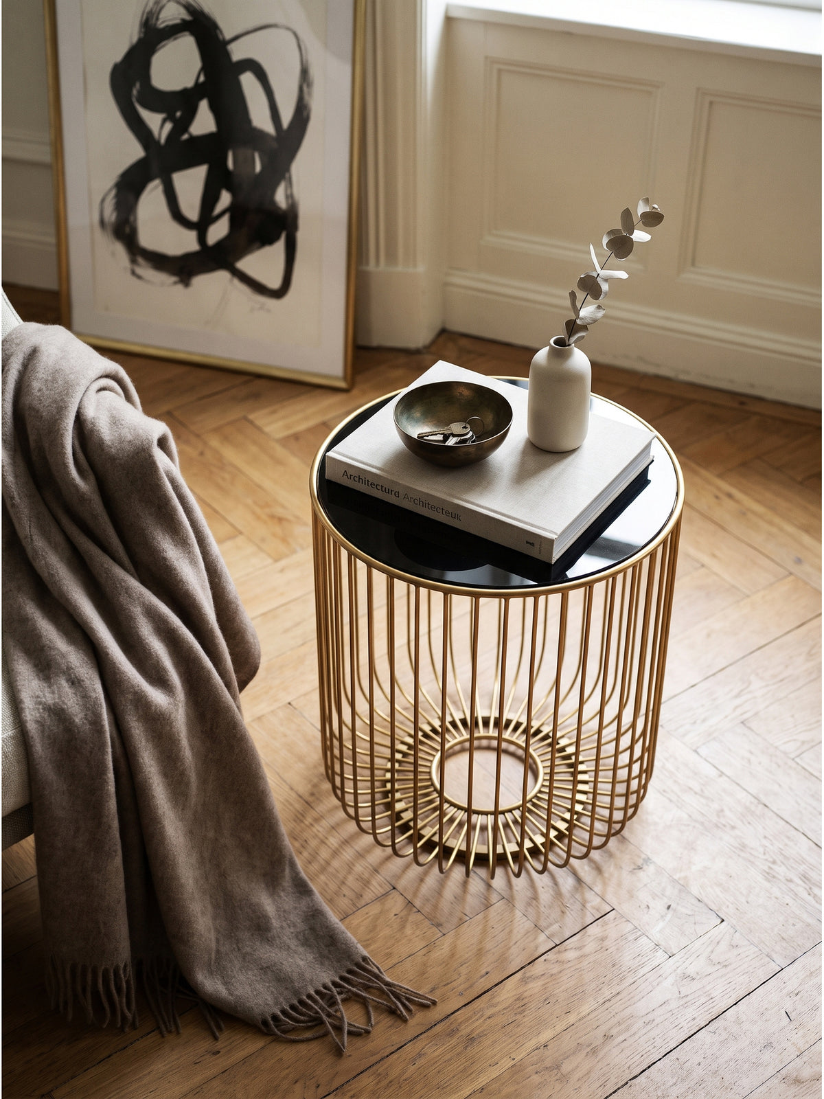 Draufsicht auf den goldenen Loungetisch mit 40cm Durchmesser aus Metall und dunklem Glas auf einem strukturierten hellen Wollteppich._