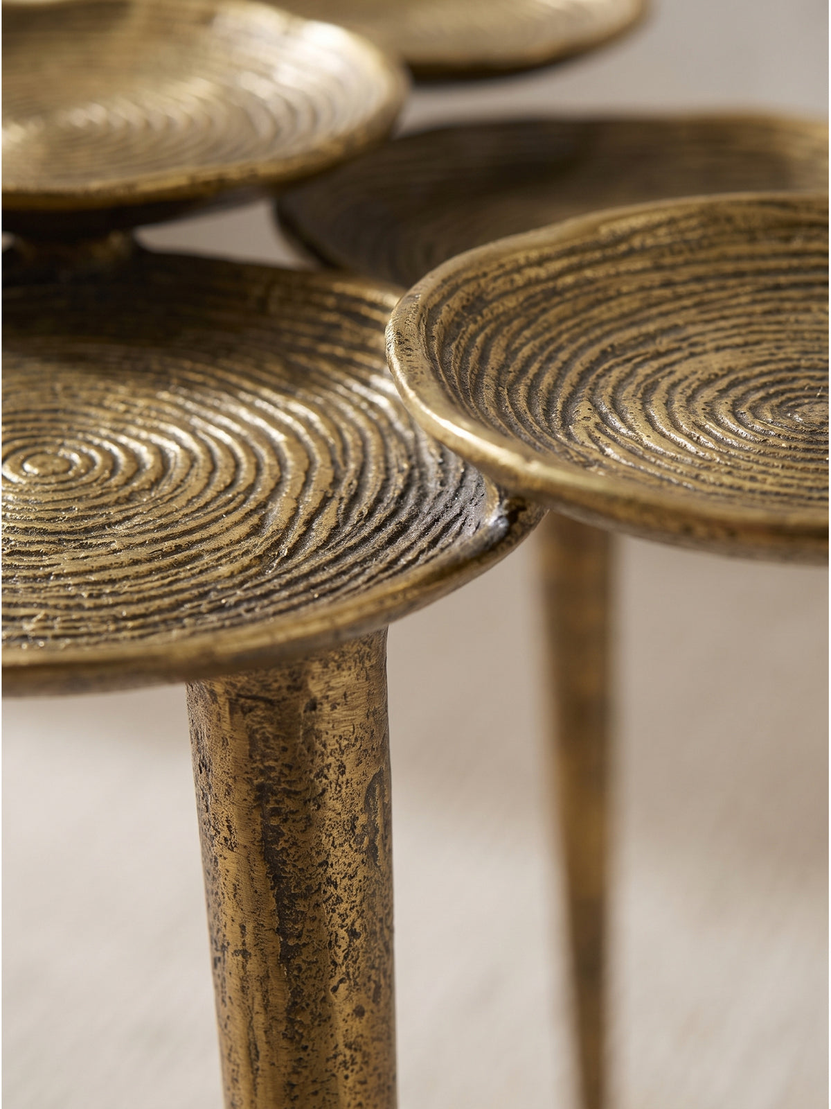 Detailansicht der handgefertigten Ringstruktur auf dem goldenen Metalltisch mit markanter, taktiler Patina._