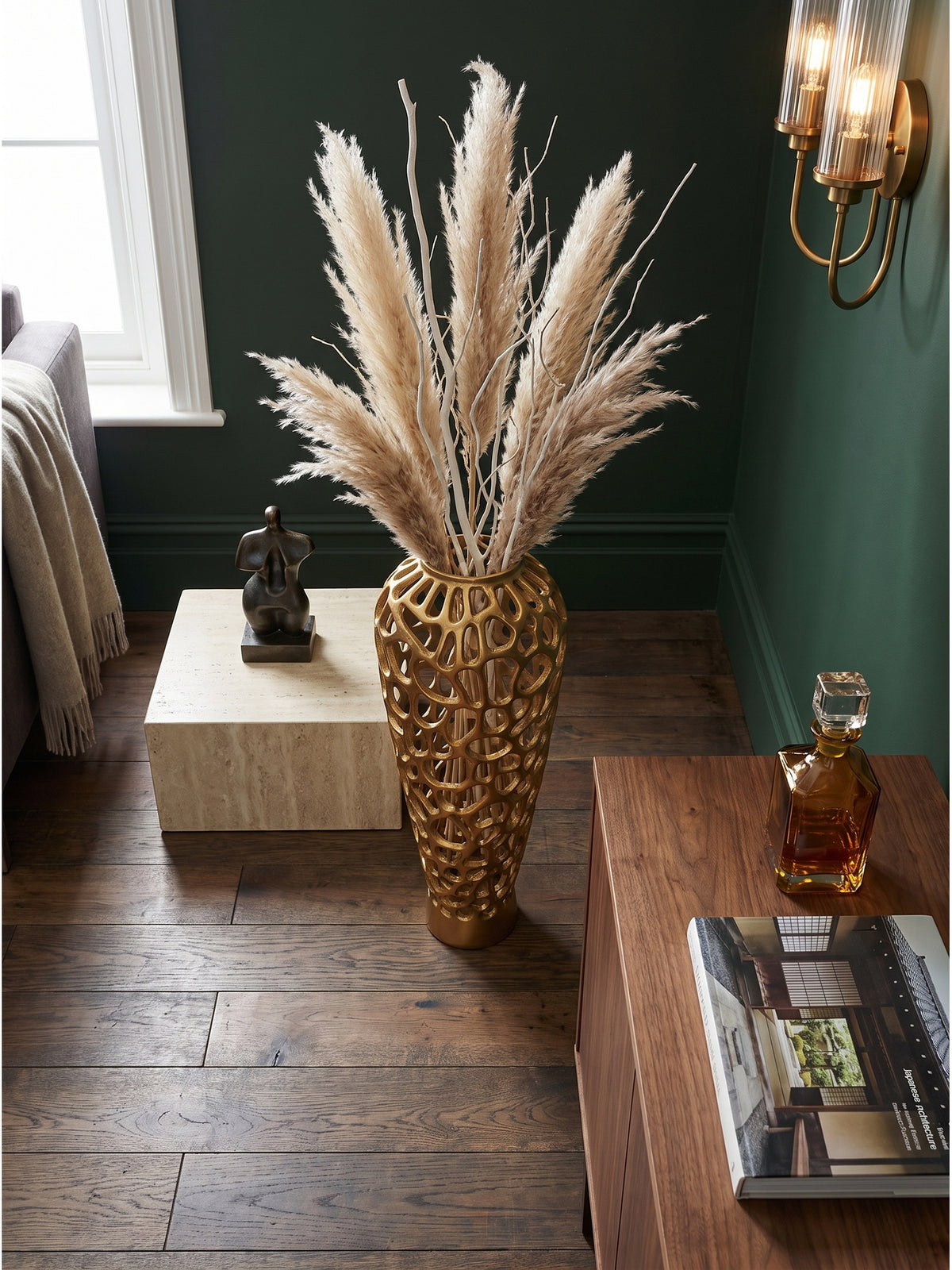 Draufsicht auf eine skulpturale goldene Bodenvase auf dunklem Eichenparkett umgeben von klassisch moderner Wohnzimmereinrichtung_