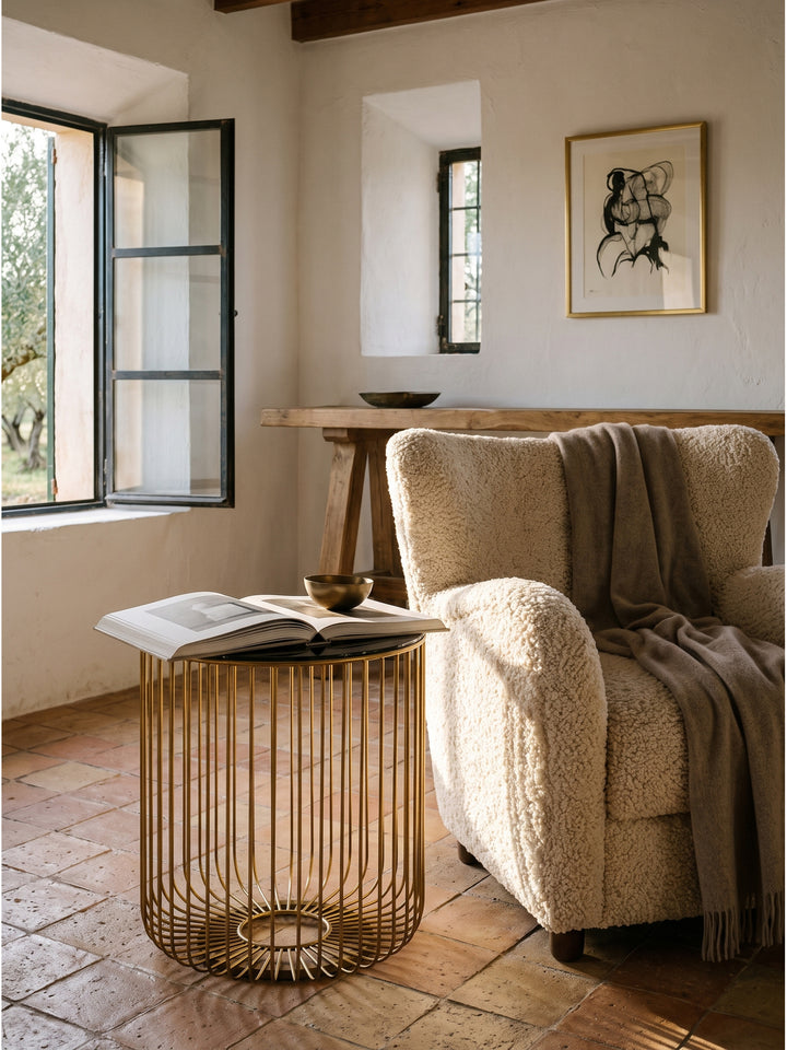 Runder Wohnzimmertisch im Korbdesign als luxuriöse Ablage neben einem gemütlichen Polstersofa in einer klassisch modernen Einrichtung._