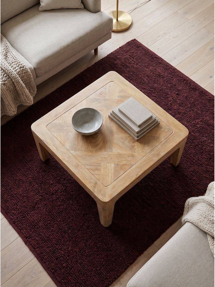 Draufsicht auf hellen Mango Couchtisch white wash in heller Sitzgruppe neben Leinensofa auf sandfarbenem Teppich_
