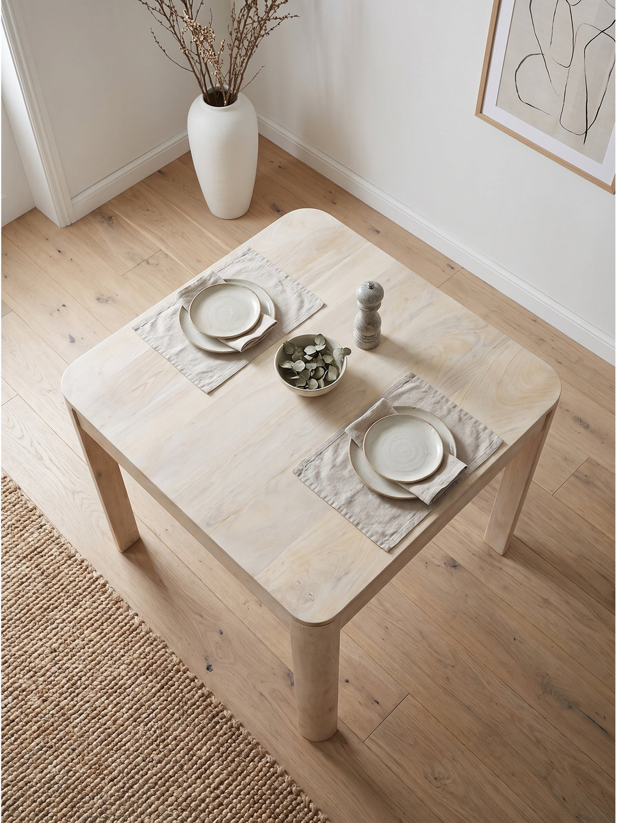 Aufsicht auf den kompakten Holztisch 80x80 cm arrangiert mit vier Stühlen auf einem Juteteppich_