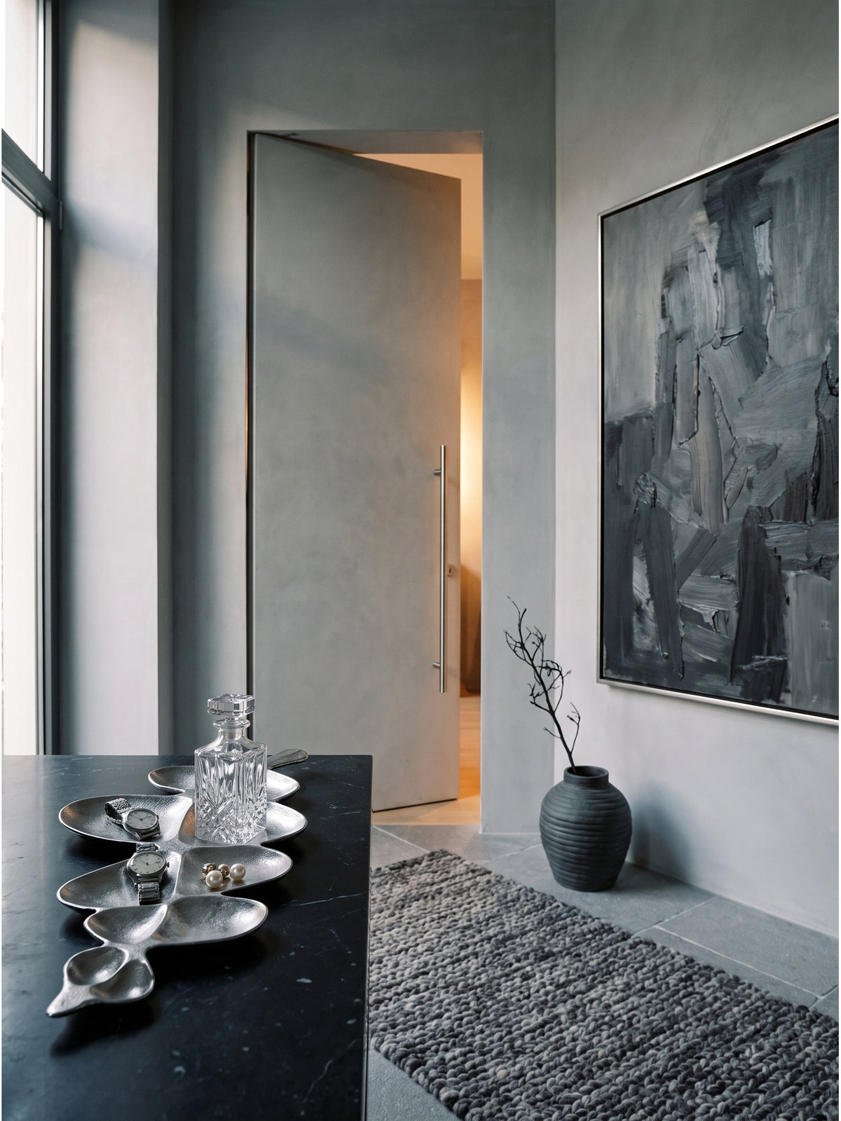Elegante Schmuckablage aus kühlem Aluminium arrangiert mit einem rahmenlosen Spiegel und schwarzen Elementen im luxuriösen Ankleidezimmer