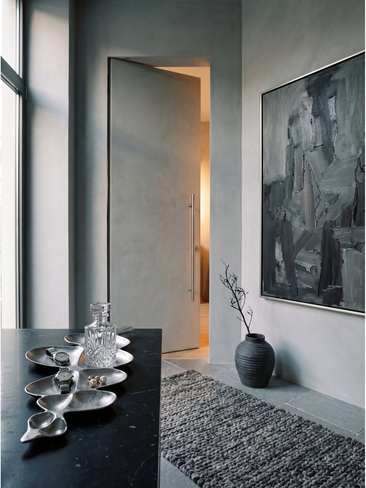 Elegante Schmuckablage aus kühlem Aluminium arrangiert mit einem rahmenlosen Spiegel und schwarzen Elementen im luxuriösen Ankleidezimmer_