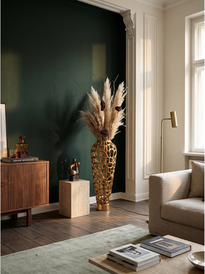 Große Bodenvase aus goldenem Aluminium mit 85 cm Höhe neben einem Leinensofa im modernen Wohnzimmer vor dunkelgrüner Akzentwand_
