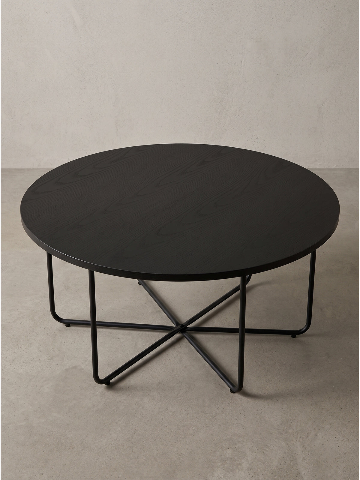 Runder Couchtisch im puristischen Design mit Eichen-Dekor in Tiefschwarz und feinen Metallverstrebungen in seitlicher Perspektive._