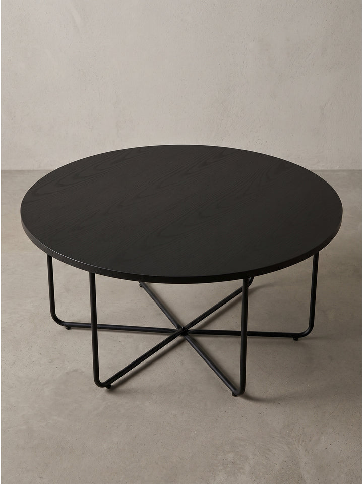 Runder Couchtisch im puristischen Design mit Eichen-Dekor in Tiefschwarz und feinen Metallverstrebungen in seitlicher Perspektive._